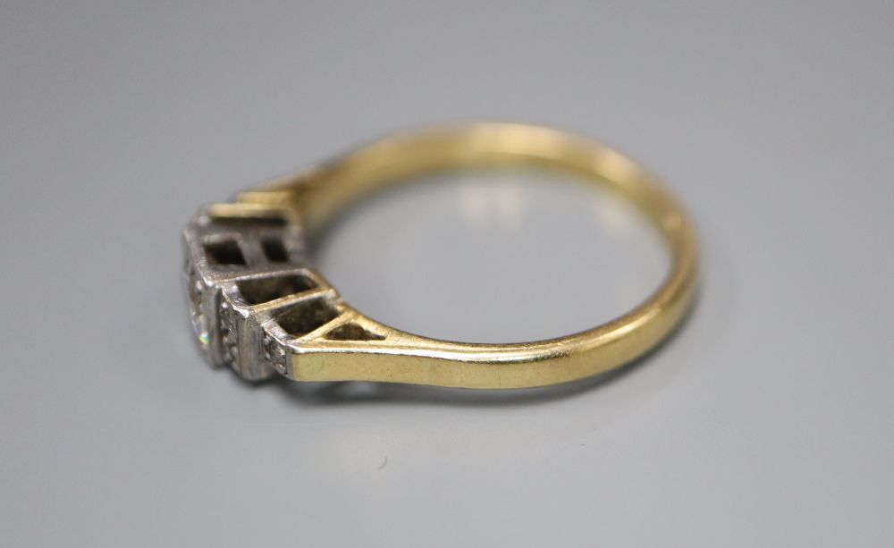 An 18ct and plat diamond ring, the square set central stone flanked each side by three further diamonds, size N, gross 3 grams.